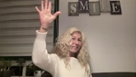 Person smiling and waving with a cozy background.