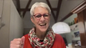 Smiling woman with gray hair in vibrant scarf.