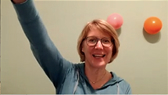 Smiling woman with raised hand and colorful balloons