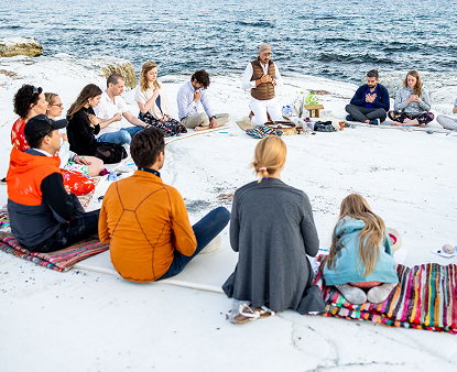 Group sitting together by the ocean shore.