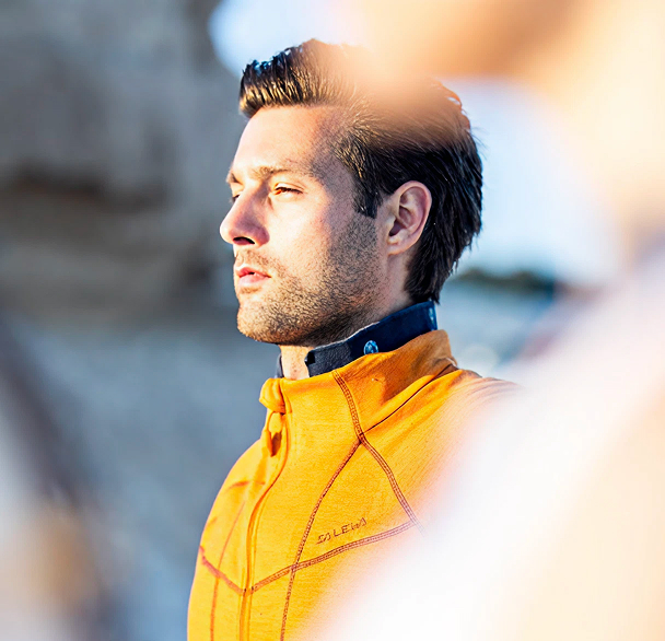 Man in orange jacket outdoors with sunlight