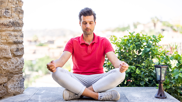 Man meditating peacefully outdoors in casual attire.
