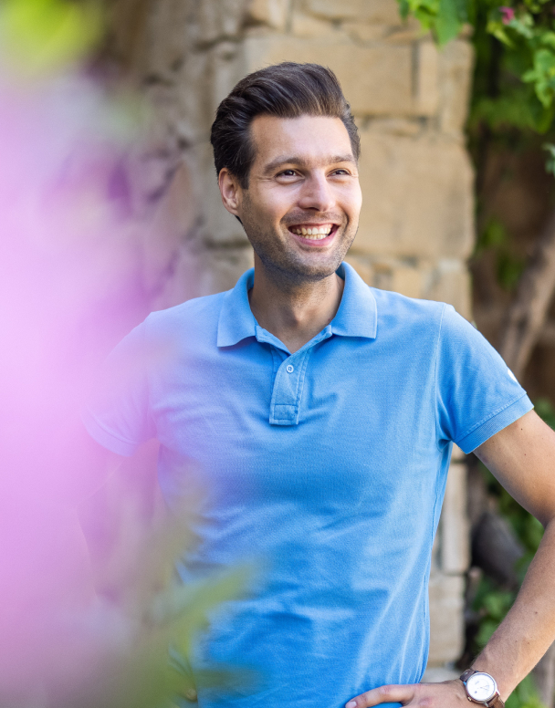 Smiling man in a blue shirt outdoors.