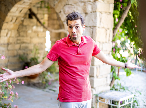 Man with a confused expression outdoors.