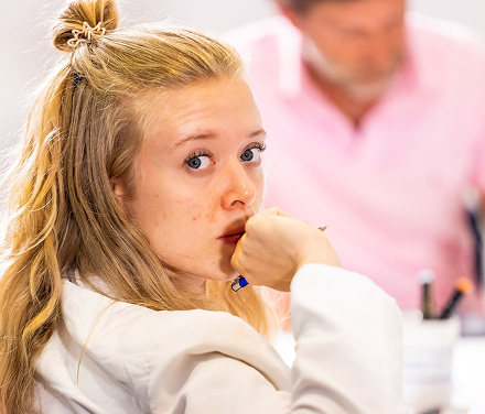Young woman with blonde hair looking thoughtful.