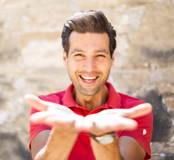 Smiling man with hands open in welcome.