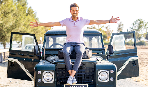 Man sitting on a vintage jeep with open doors.