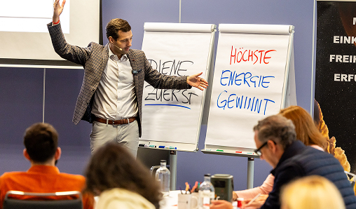 Presenter speaking in a seminar with whiteboards.
