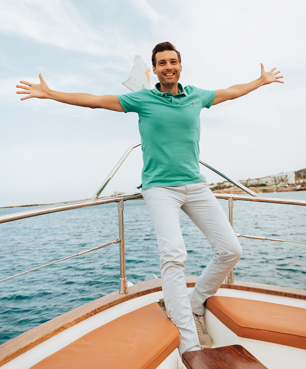 Man joyfully posing on a boat at sea.