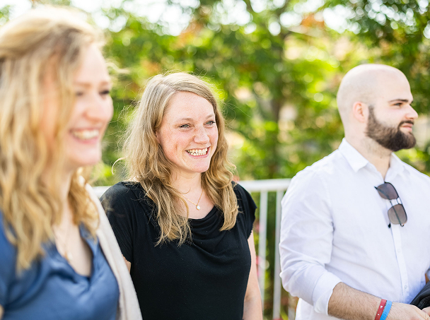 Three people smiling outdoors in natural light.