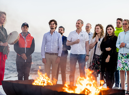 Group gathered around a fire by the beach.