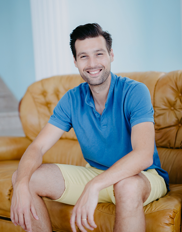 Smiling man sitting on a yellow sofa.