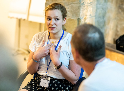 Person speaking in a group discussion setting.