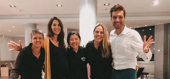 Group of five people smiling together indoors.