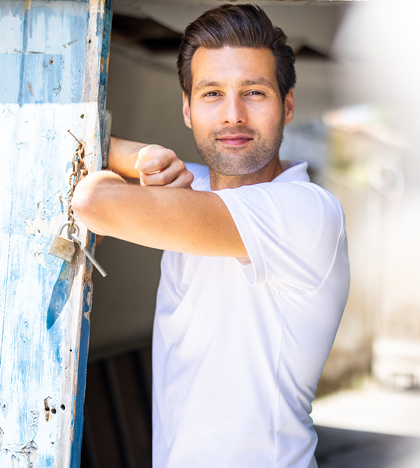 Man leaning on a door with a lock.