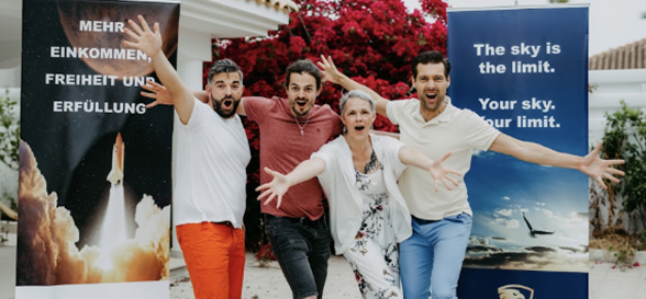 Four excited people celebrating under promotional banners.