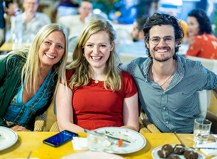 Three friends smiling at a social gathering.