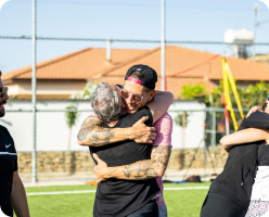 Two people hugging joyfully on a field.