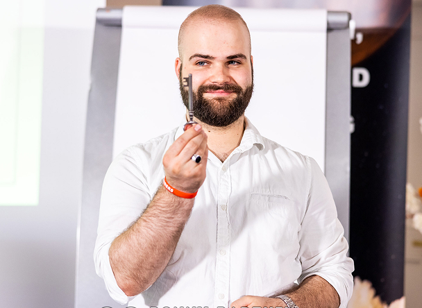 Smiling man holding a pen in front of a board.