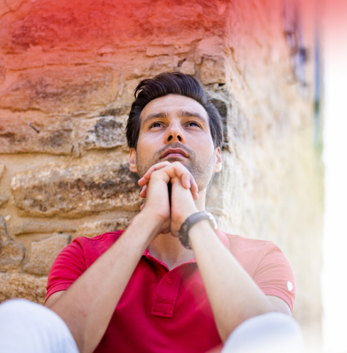 Thoughtful man resting against a stone wall.