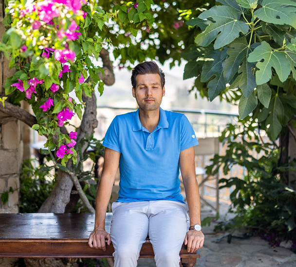 Man sitting peacefully among vibrant flowers