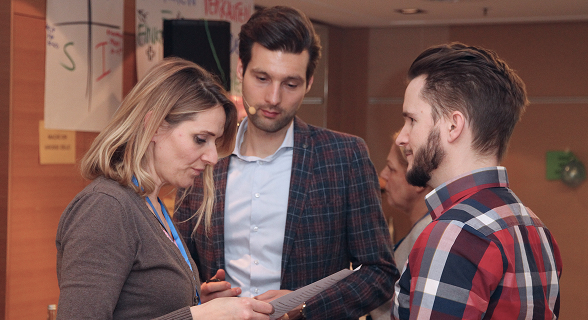 Three people discussing documents in a meeting.