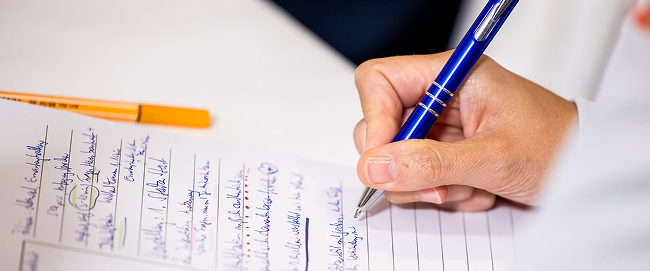 Hand writing notes with a blue pen.