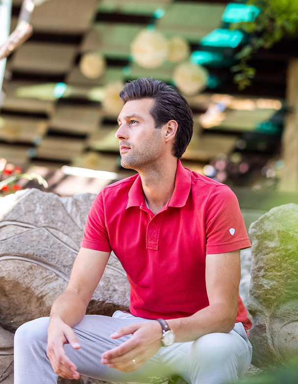 Man in red shirt sitting on a rock.