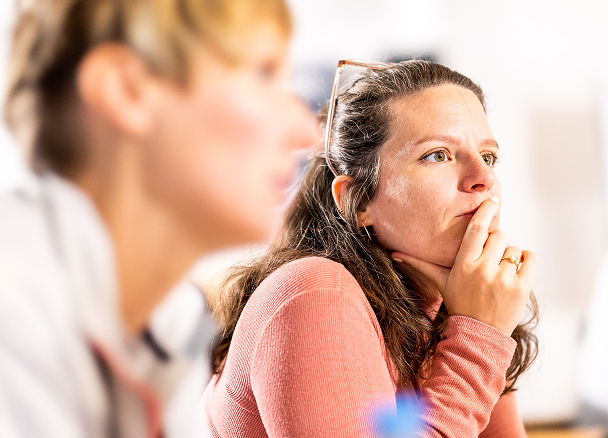 Thoughtful woman in a discussion setting.