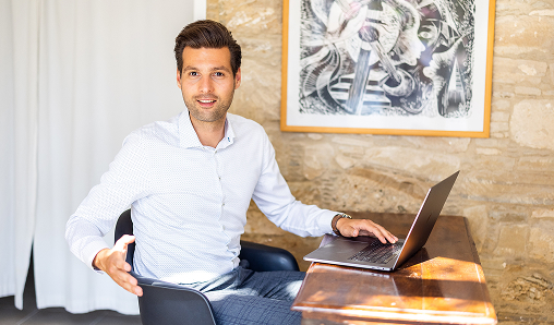 Man working on laptop at a wooden desk.