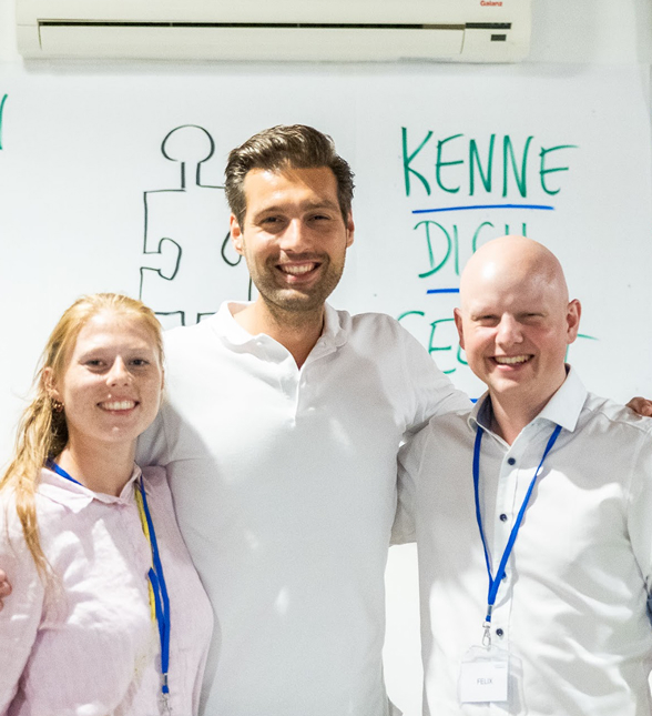 Three people smiling in a conference setting.